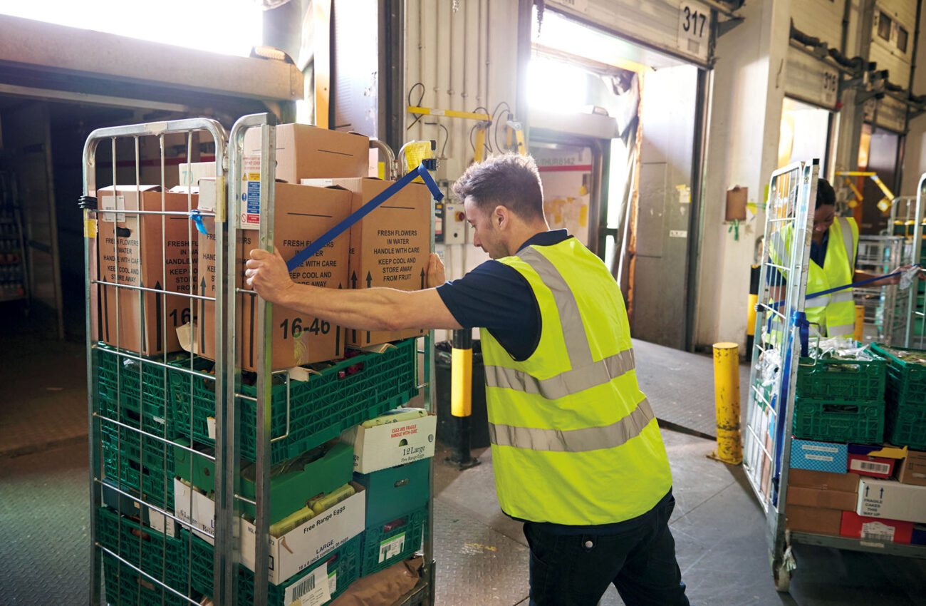 Man pushing a roll cage ready for delivery in a warehouse